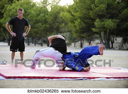 "Two men doing martial arts on a mat, man watching" View Large Photo Image Stock Photography - "Two men doing martial arts on a mat, man watching". Fotosearch