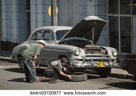 "Two men repairing a vintage car in a street of Cienfuegos, Cienfuegos, Cienfuegos Province, Cuba, North America" View Large Photo Image Stock Photo - "Two men repairing a vintage car in a street of Cienfuegos, Cienfuegos, Cienfuegos Province, Cuba, North America". Fotosearch