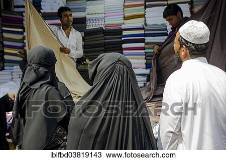 Stock Image - "Two Muslim women and a man buying material at Mangaldas Market, Mumbai, Maharashtra, India, Asia". Fotosearch