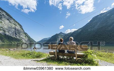 Stock Image - "Two people sitting on a bench, looking over Lake Konigssee, St. Bartholoma in Konigssee, Berchtesgaden National Park, Berchtesgadener Land district, Upper Bavaria, Bavaria, Germany, Europe". Fotosearch
