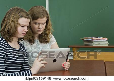 "Two schoolgirls in the classroom using a tablet PC, Germany, Europe" View Large Photo Image Stock Photograph - "Two schoolgirls in the classroom using a tablet PC, Germany, Europe". Fotosearch