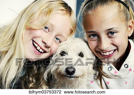 Stock Image - "Two sisters, 11 years and 8 years, with their dog". Fotosearch