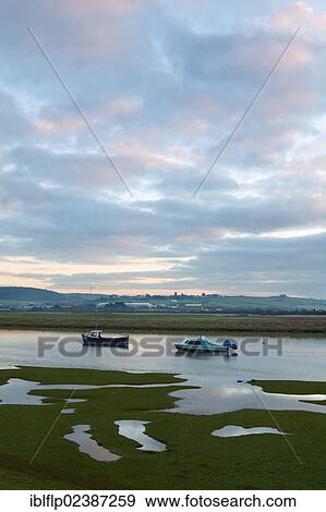 "Two small boats rising with incoming tide on tidal stretch of river at dawn, River Caen, near Braunton Marsh, Braunton, North Devon, England, United Kingdom, Europe" View Large Photo Image Stock Photo - "Two small boats rising with incoming tide on tidal stretch of river at dawn, River Caen, near Braunton Marsh, Braunton, North Devon, England, United Kingdom, Europe". Fotosearch