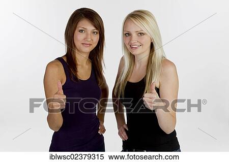 Two smiling young women making thumbs up gesture View Large Photo Image Stock Photography - Two smiling young women making thumbs up gesture. Fotosearch