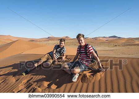 "Two teenagers sitting exhausted on a dune, Sossusvlei, Namib Desert, Namibia, Africa" View Large Photo Image Picture - "Two teenagers sitting exhausted on a dune, Sossusvlei, Namib Desert, Namibia, Africa". Fotosearch