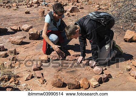 Picture - "Two tourists looking for fossilised dinosaur footprints, Kalkfeld, Otjozondjupa Region, Namibia, Africa". Fotosearch