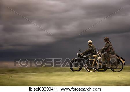 "Two vintage motorcyclists in front of a dramatic cloudy sky, Mindelheim, Unterallgau District, Bavaria, Germany, Europe" View Large Photo Image Stock Image - "Two vintage motorcyclists in front of a dramatic cloudy sky, Mindelheim, Unterallgau District, Bavaria, Germany, Europe". Fotosearch