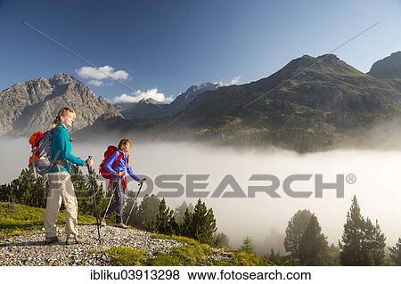 "Two women hiking, low-hanging clouds in the Fuorn Pass, Swiss National Park, Graubunden, Switzerland, Europe" View Large Photo Image Stock Photo - "Two women hiking, low-hanging clouds in the Fuorn Pass, Swiss National Park, Graubunden, Switzerland, Europe". Fotosearch