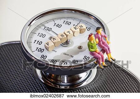 Stock Photo - "Two women, miniature figures, sitting on the edge of scales, cubes with letters forming the word """"Fasten"""", German for """"fasting"""", symbolic image for dieting, nutritional regimen". Fotosearch