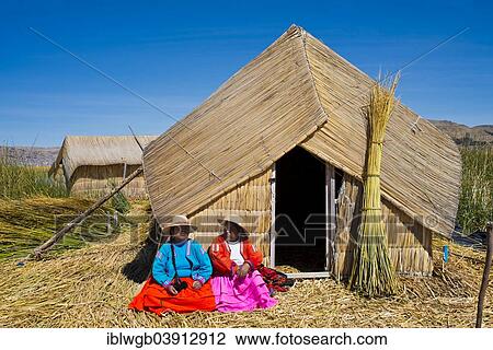 "Two women of the Uro Indians wearing traditional dress sitting in front of a reed hut, floating islands made of totora reeds, Lake Titicaca, southern Peru, Peru, South America" View Large Photo Image Stock Image - "Two women of the Uro Indians wearing traditional dress sitting in front of a reed hut, floating islands made of totora reeds, Lake Titicaca, southern Peru, Peru, South America". Fotosearch