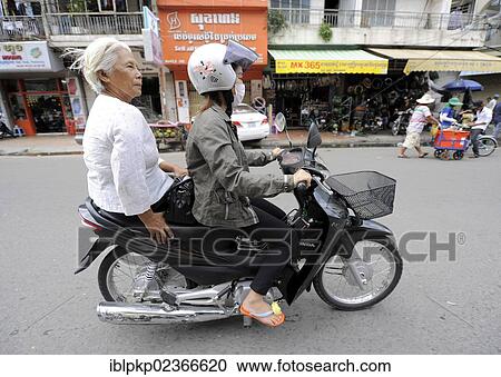 Stock Image - "Two women on a motor scooter, Phnom Penh, Cambodia, Southeast Asia, Asia". Fotosearch