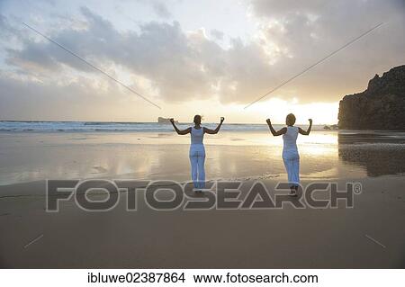 Two women relaxing by doing yoga on the beach at sunset View Large Photo Image Picture - Two women relaxing by doing yoga on the beach at sunset. Fotosearch