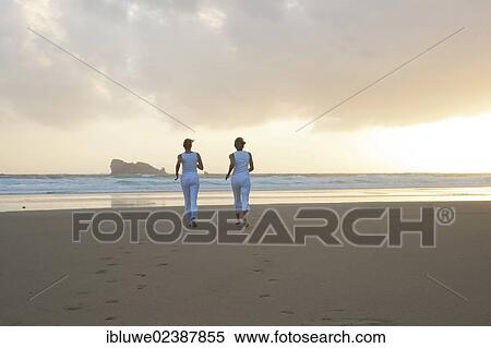 Two women running along the beach at sunset View Large Photo Image Stock Photography - Two women running along the beach at sunset. Fotosearch