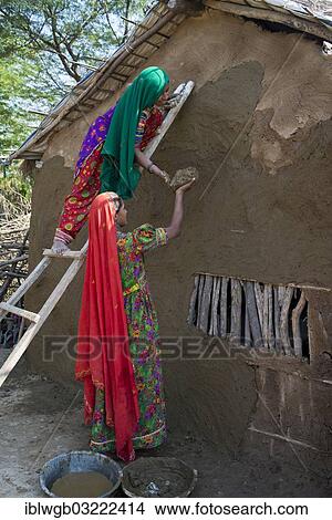 "Two women wearing traditional saris rendering a house wall with a mixture of clay, sand and cow dung, Rann of Kutch, Gujarat, India, Asia" View Large Photo Image Picture - "Two women wearing traditional saris rendering a house wall with a mixture of clay, sand and cow dung, Rann of Kutch, Gujarat, India, Asia". Fotosearch
