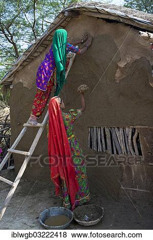 "Two women wearing traditional saris rendering a house wall with a mixture of clay, sand and cow dung, Rann of Kutch, Gujarat, India, Asia" View Large Photo Image Stock Photo - "Two women wearing traditional saris rendering a house wall with a mixture of clay, sand and cow dung, Rann of Kutch, Gujarat, India, Asia". Fotosearch