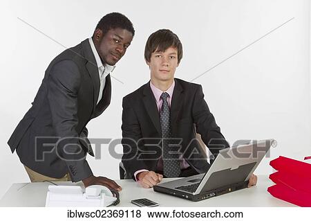 Stock Photo - Two young businessmen of different races with a laptop. Fotosearch