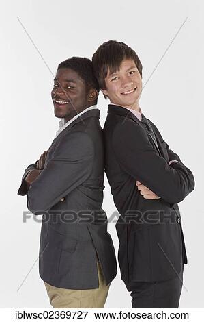 Stock Photo - Two young businessmen standing back to back with their arms folded and smiling. Fotosearch