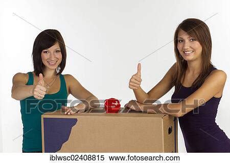 "Two young woman with moving boxes and a piggy bank, making a thumbs-up gesture" View Large Photo Image Stock Photography - "Two young woman with moving boxes and a piggy bank, making a thumbs-up gesture". Fotosearch