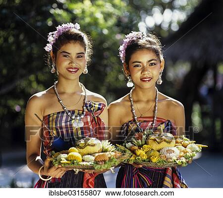 "Two young women dressed in traditional costumes holding trays of carved exotic fruits, Rose Garden, Thailand, Asia" View Large Photo Image Stock Photo - "Two young women dressed in traditional costumes holding trays of carved exotic fruits, Rose Garden, Thailand, Asia". Fotosearch