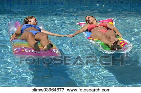 "Two young women, friends, holding hands, relaxing on air mattress in pool, Puerto del Carmen, Lanzarote, Canary Islands, Spain, Europe" View Large Photo Image Stock Photo - "Two young women, friends, holding hands, relaxing on air mattress in pool, Puerto del Carmen, Lanzarote, Canary Islands, Spain, Europe". Fotosearch