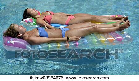 "Two young women, friends, holding hands, relaxing on air mattress in pool, Puerto del Carmen, Lanzarote, Canary Islands, Spain, Europe" View Large Photo Image Stock Photograph - "Two young women, friends, holding hands, relaxing on air mattress in pool, Puerto del Carmen, Lanzarote, Canary Islands, Spain, Europe". Fotosearch