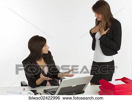Two young women having a discussion in an office View Large Photo Image Stock Photograph - Two young women having a discussion in an office. Fotosearch