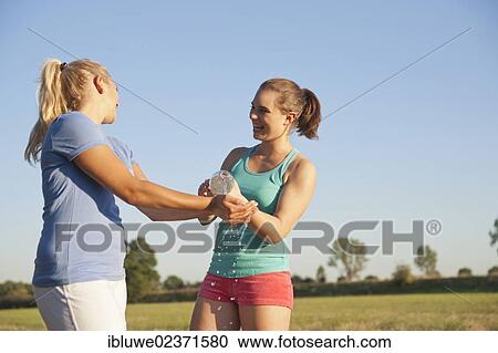 Two young women having fun with a bottle of water during a drink break while doing sports View Large Photo Image Stock Image - Two young women having fun with a bottle of water during a drink break while doing sports. Fotosearch