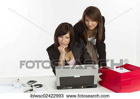 Two young women in an office looking at a laptop View Large Photo Image Stock Image - Two young women in an office looking at a laptop. Fotosearch