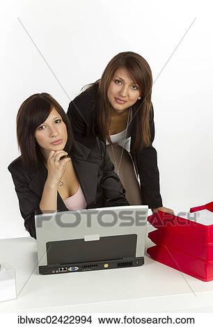 Picture - Two young women in an office. Fotosearch