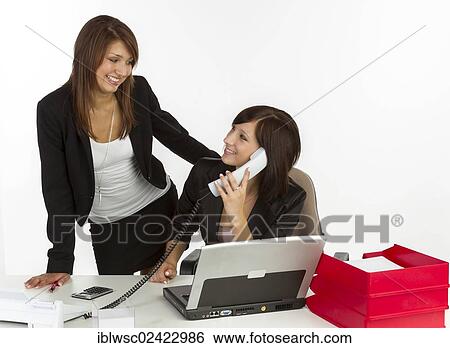 Two young women in an office View Large Photo Image Stock Photograph - Two young women in an office. Fotosearch