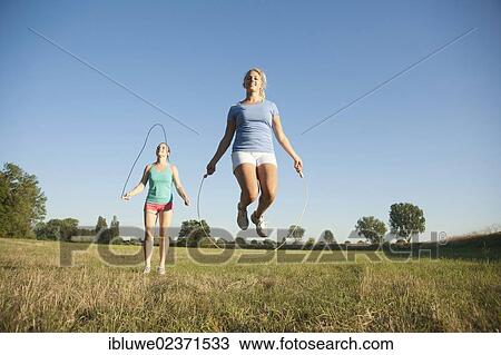 Two young women jumping rope in a meadow View Large Photo Image Stock Image - Two young women jumping rope in a meadow. Fotosearch