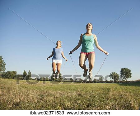 Two young women jumping rope in a meadow View Large Photo Image Stock Photo - Two young women jumping rope in a meadow. Fotosearch