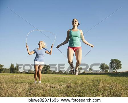 Two young women jumping rope in a meadow View Large Photo Image Stock Photography - Two young women jumping rope in a meadow. Fotosearch
