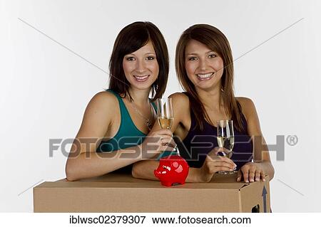 "Two young women moving house, with a piggy bank and glasses of champagne" View Large Photo Image Stock Photo - "Two young women moving house, with a piggy bank and glasses of champagne". Fotosearch