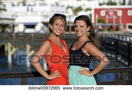 Stock Photography - "Two young women posing on the redesigned promenade of Playa Blanca, Lanzarote, Canary Islands, Spain, Europe". Fotosearch