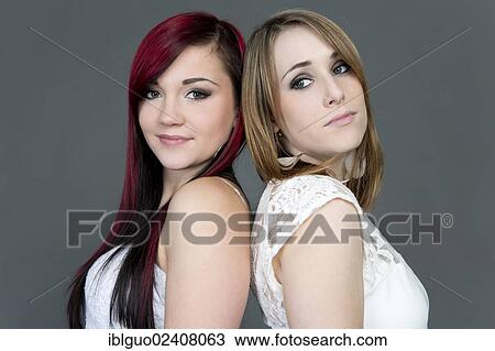 Stock Image - "Two young women standing back to back, portrait". Fotosearch