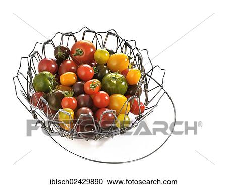 Stock Image - Various wild tomatoes in a wire basket. Fotosearch