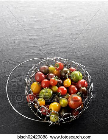 Stock Photo - "Various wild tomatoes in a wire basket, on a slate". Fotosearch