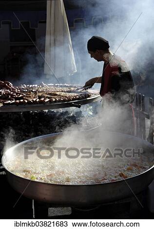 "Vegetables boiling in a large pan and man preparing meats on giant barbecue at the annual All Saints Market in Cocentaina, Alicante province, Spain, Europe" View Large Photo Image Stock Image - "Vegetables boiling in a large pan and man preparing meats on giant barbecue at the annual All Saints Market in Cocentaina, Alicante province, Spain, Europe". Fotosearch