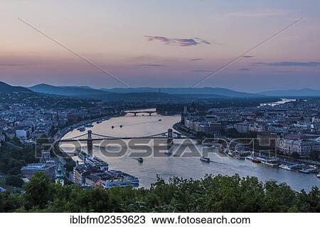 Stock Image - "View from the Citadel to the Danube, Buda and Pest, bridges over the Danube, Chain Bridge at front, Margaret Bridge at back, dusk, Budapest, Hungary, Europe". Fotosearch