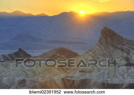 Stock Image - "View from Zabriskie Point or Zabriske Point, eroded rocks discoloured by minerals, Manly Beacon, sunset, Panamint Range at back, Death Valley National Park, Mojave Desert, California, USA". Fotosearch