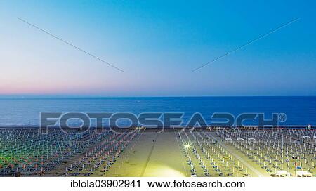 Stock Image - "View of a beach with sunshades and sun beds at twilight, 5 am, image 1 of 9, Lignano Sabbiadoro, Udine province, Adriatic Coast, Italy, Europe". Fotosearch