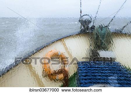 Stock Image - "View through the wet window of the bow of the shrimp boat """"Columbus"""" from Pellworm island, travelling in North Frisian coastal waters, Pellworm, Schleswig-Holstein, Germany, Europe". Fotosearch