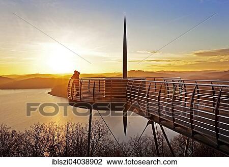 Stock Image - "Viewing platform Biggeblick with a person at sunset, Biggesee reservoir, Attendorn, Sauerland, North Rhine-Westphalia, Germany, Europe". Fotosearch