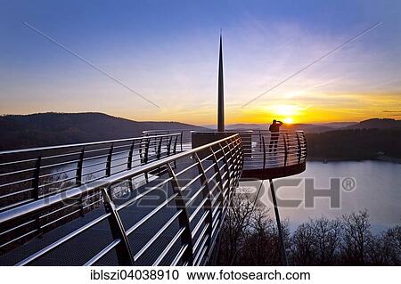 Stock Image - "Viewing platform Biggeblick with a person at sunset, Biggesee reservoir, Attendorn, Sauerland, North Rhine-Westphalia, Germany, Europe". Fotosearch