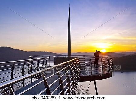 Stock Image - "Viewing platform Biggeblick with a person at sunset, Biggesee reservoir, Attendorn, Sauerland, North Rhine-Westphalia, Germany, Europe". Fotosearch