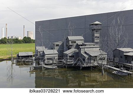 Stock Image - "Village on stilts in front of an industrial scene, art installation """"The Settlement of Hans op de Beek"""", Emscherkunst 2013, open air art exhibition, Dinslaken, Ruhr district, North Rhine-Westphalia, Germany, Europe". Fotosearch