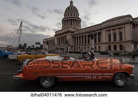 Stock Photograph - "Vintage Buick from the 1950s in front of the Capitol at dusk, Havana, Cuba, North America". Fotosearch