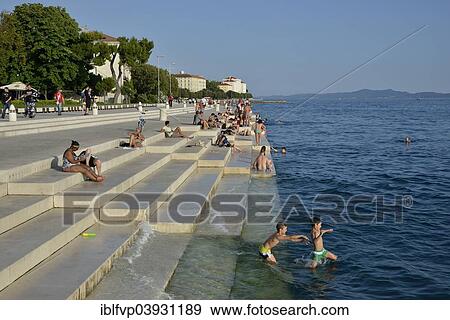 "Visitors basking in the evening sun at the Sea Organ by architect Nikola Basic, Zadar, Dalmatia, Croatia, Europe" View Large Photo Image Stock Photo - "Visitors basking in the evening sun at the Sea Organ by architect Nikola Basic, Zadar, Dalmatia, Croatia, Europe". Fotosearch