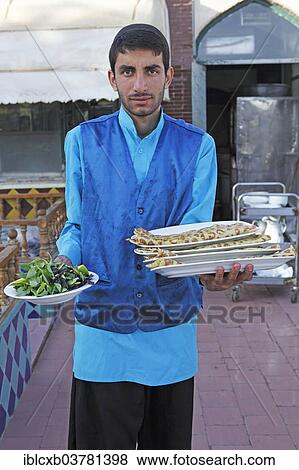 Stock Photo - "Waiter serving bread and salad in a traditional restaurant, Bazaar, Isfahan, Isfahan Province, Persia, Iran, Asia". Fotosearch